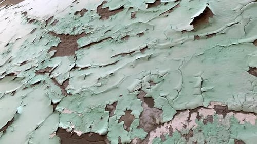 Cracked plaster on a house wall. Destroyed green color paint on the wall. Grungy texture of old weat