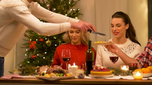 Happy friends enjoying christmas dinner feast at home with Turkey and wine