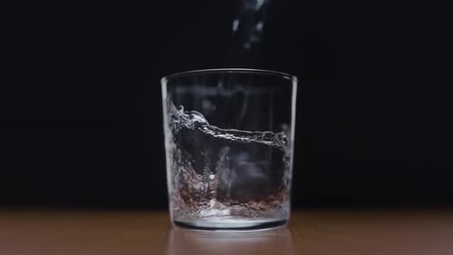 Water Poured Into Glass on Black Background