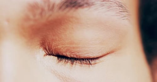 Close face zoom of a brown eye opening to blink with healthy iris, retina and cornea of a man