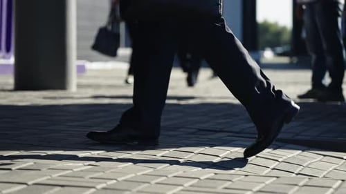 Nahaufnahme eines städtischen Bürgersteigs in der Nähe von Fußgängern, die Beine und Schuhe in Bewegung beim Überqueren zeigen