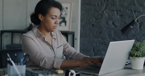 Portrait d'une femme d'affaires tapant à l'aide d'un ordinateur portable travaillant seule dans un bureau moderne
