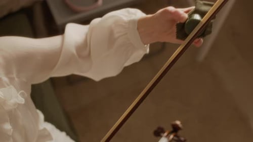 Woman Teacher Applying Rosin to Violin Bow during Music Lesson