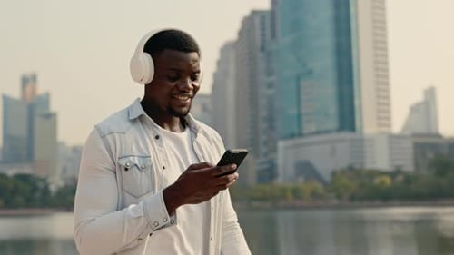 Portrait of African American Man Walking in the Park with Smartphone Listen Music