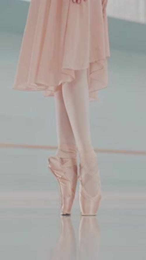 Close-up of ballerina's legs in pointe shoes. Ballerina is standing on tiptoe. Vertical video format