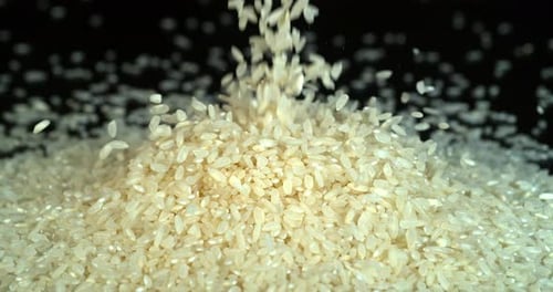 Riz tombant sur fond noir, slow motion 4K