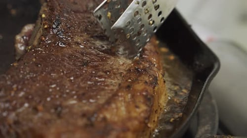 Frying meat steak inside frying pan. Close up slow motion shot.