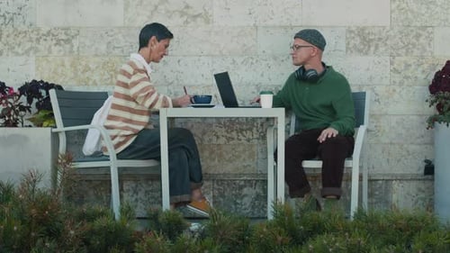 Two Colleagues Working At Cafe Table Outdoors