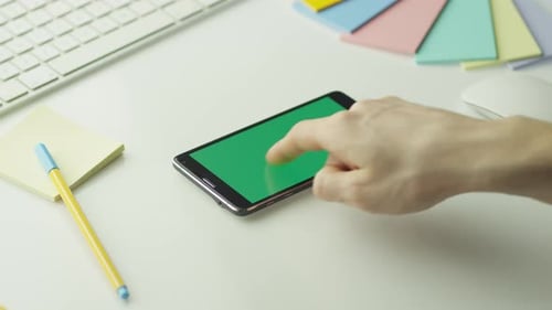 O designer está usando um telefone Android com tela verde no modo paisagem.