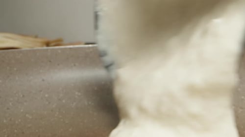 I pour the pancake batter into the pan. Dolly slider extreme close-up.