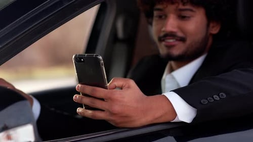 Young Adult in Car Uses Smart Phone