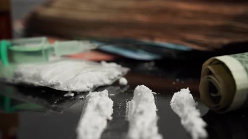 Syringe for injection and cocaine powder, on a black background.