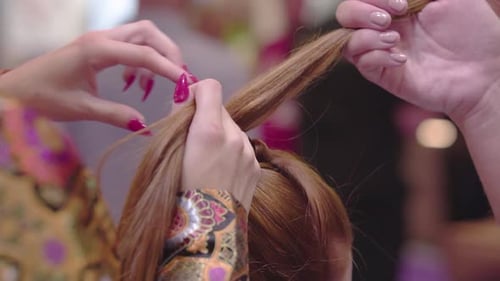 close up of hairdresser with fashionable jacket red nails creating hairstyle on brunette female slow