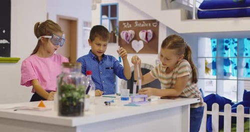 Children Conduct Science Experiment Together Indoors at White Table