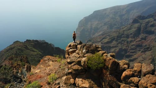 Brave Strong Woman Hiker Stands at Mountain Top Cliff Edge
