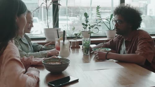 Group of Multi-ethnic People Talking, Having Lunch, Drinking Cocktails in Cafe