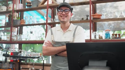 Smiling Young Adult in Apron Behind Retail Counter