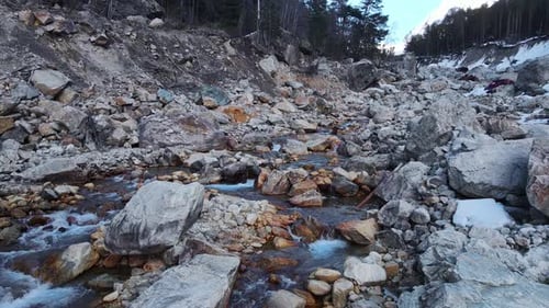 Water Flows Through Rocky Terrain Surrounded By Trees in a Natural Landscape