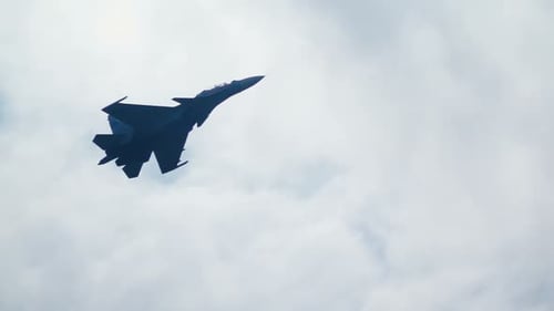 Jet Fighter Soaring Through Cloudy Blue Sky