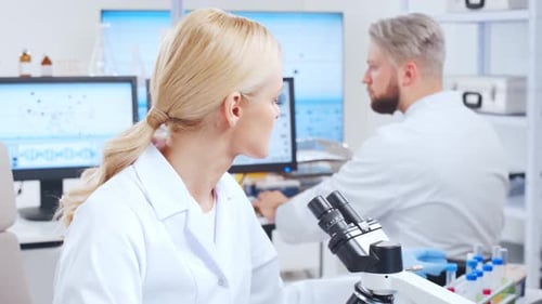 Woman Analyzing Sample with Microscope in Laboratory