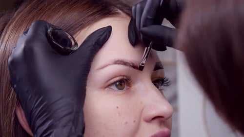 Cosmetic Artist Applying Eyebrow Tint To Client