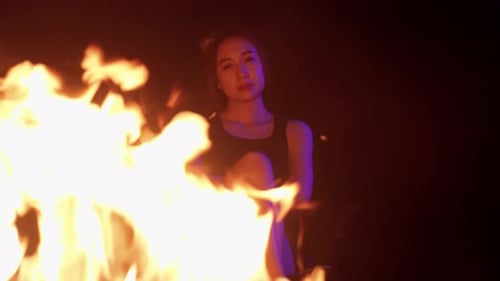 Woman Sits by Fire at Night