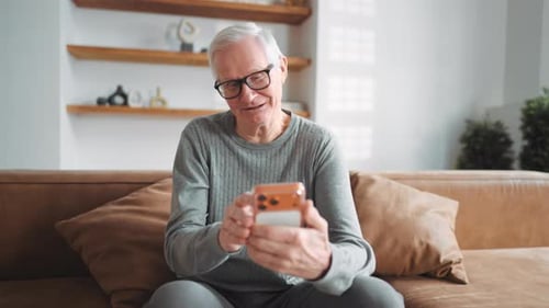 Senior Man Using Smartphone on Couch at Home