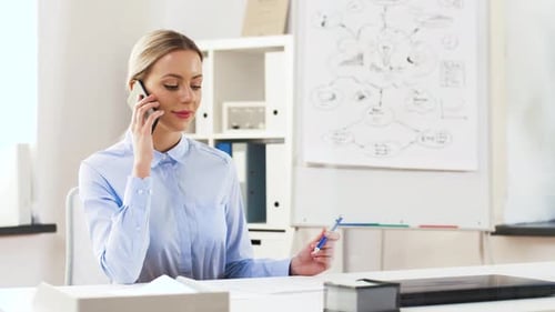 Happy businesswoman talking on smartphone at modern office through glass wall
