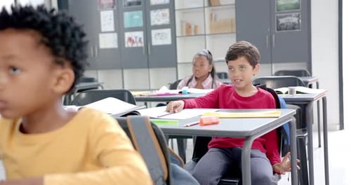 In der Schule sitzen Kinder an Schreibtischen mit bunten Utensilien im Klassenzimmer