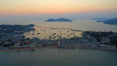 Drone shot traveling slowly forward above an island with a little city build on the isthmus during s