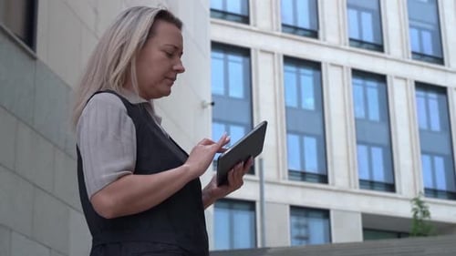 A Woman Works on a Tablet in a Business City Technology Business Concept