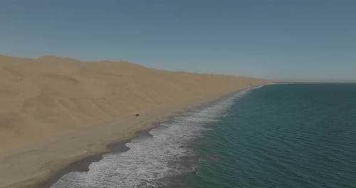 Aerial view of desert dunes and vehicle at Sandwich Harbour, Namibia.