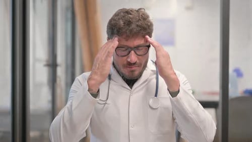 Stressed Doctor Massaging Temples in Hospital Office