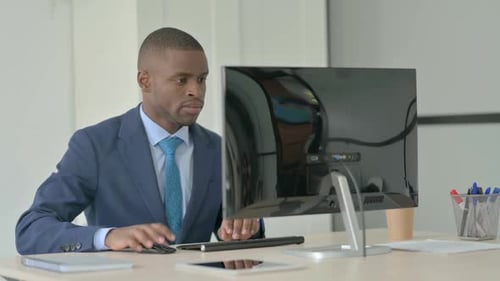Man in Suit Typing at Computer in Office