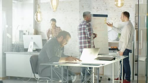 Multiple Activities in Creative Office. People Draw on Whiteboard. Use Personal Computers. Leave O