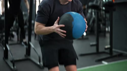 Closeup of Dedicated Beginner Sportsman Training Using Heavy Fitness Ball in Gym Motivated Athlete