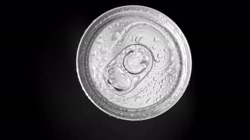 A close-up view of the top of a beverage can with water droplets.
