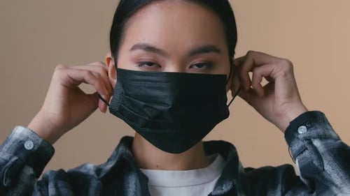 Young Woman Puts on a Black Medical Face Mask