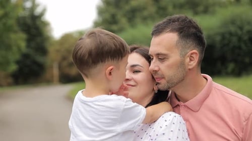 Happy Parents Mom and Dad Hold Their Son in Their Arms While Standing in the City Park