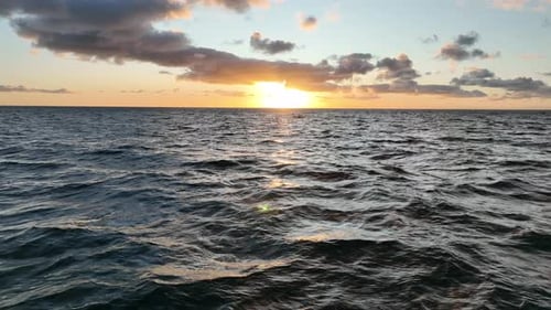 Flying low over ocean at sunrise. Camera files low and slow towards sun rising over the ocean. Shot