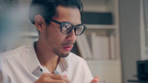 Asian young businessman eating noodles while working in office at night.