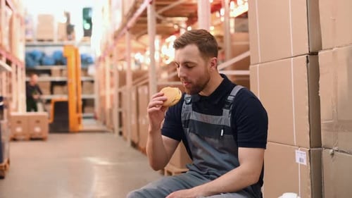 Lunch time. Eating and drinking. Storage worker in uniform is in the warehouse
