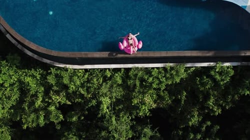 Top View of Millennial Young Woman Swim with Inflatable Pink Flamingo