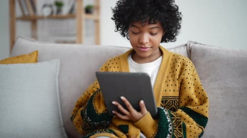 Woman Using Tablet on Couch Indoors