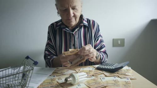 Mature Woman Counting Money at Her Table