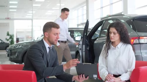 A Young Man and Woman are Consulting with a Car Dealership Manager About a New Car Model at a Car
