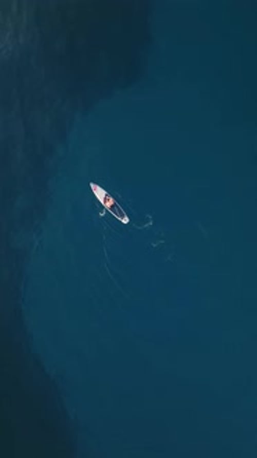 Vertical Video Aerial View of a Paddle Board a Man is Sailing on the Blue Sea