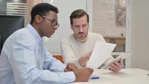 Men Collaborating in Modern Office Reviewing Paperwork