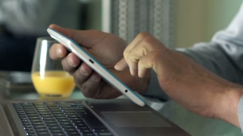 Man Using Tablet Next to Laptop and Juice