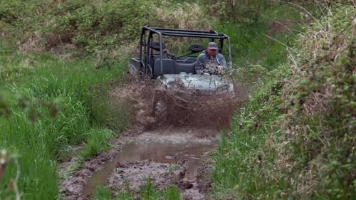 Zeitlupe mit Mann fährt ATV durch Schlamm